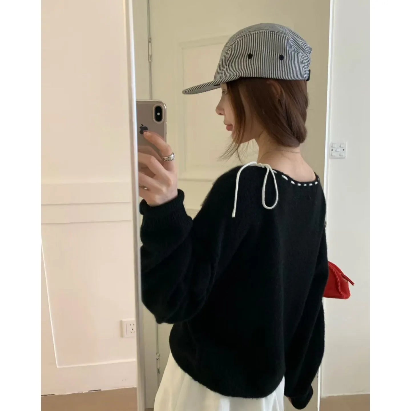 A grey women's loose-fitting knitwear pullover on a hanger, showing its casual style.