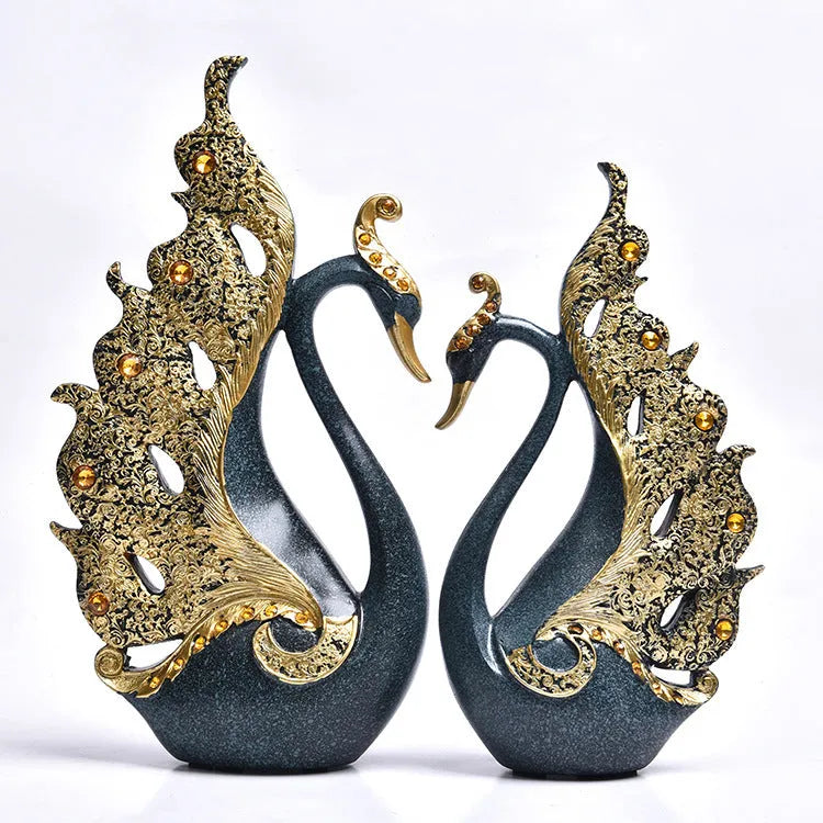Resin couple swan figurines in blue and gold, large 29cm and small 24cm, on a wooden table