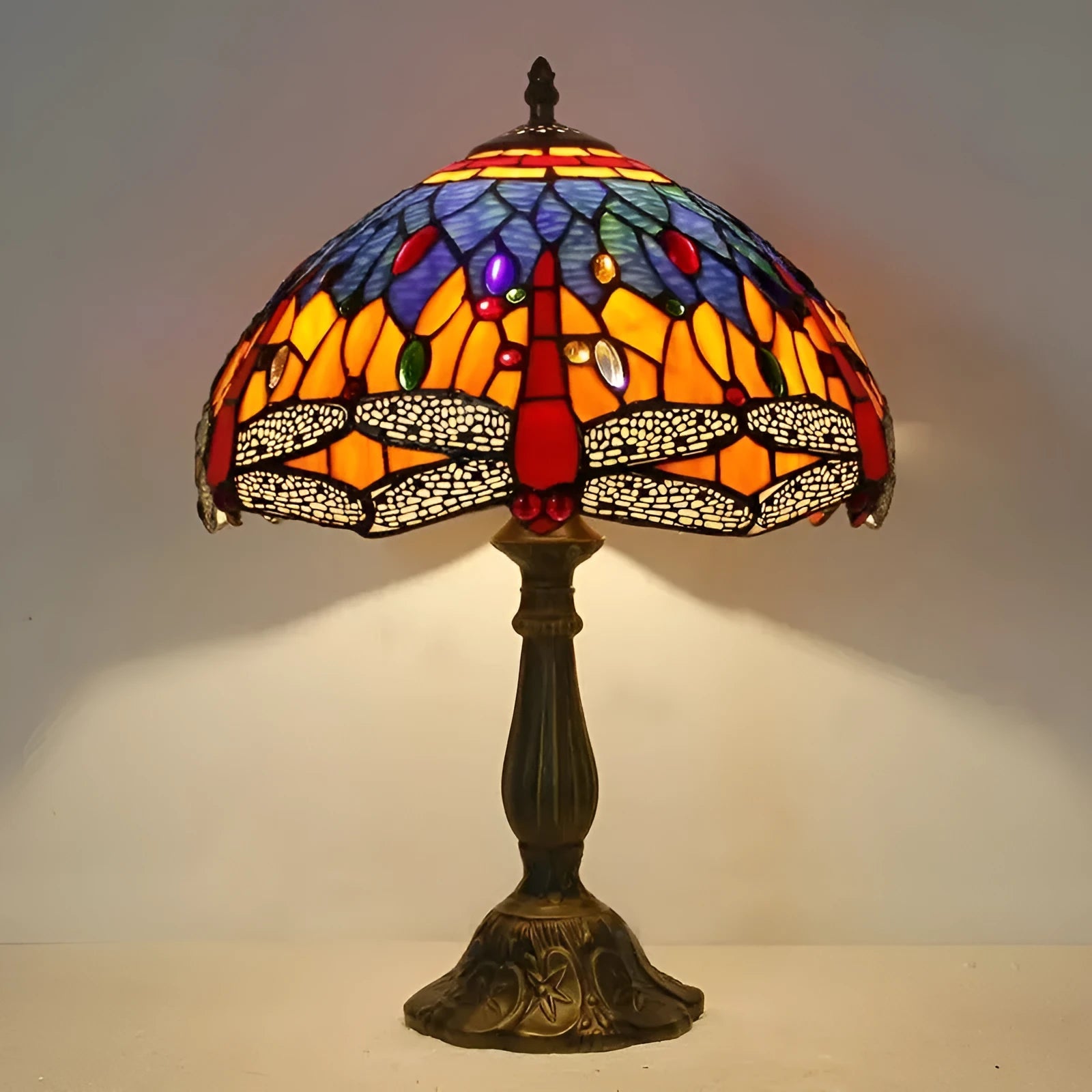 Tiffany-style stone table lamp with blue dragonfly design on a wooden surface.