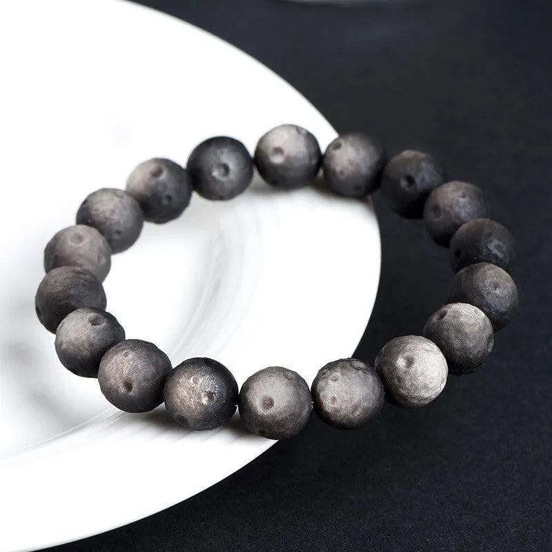 Natural obsidian crater ball bracelet in silver or gold finish, showing textured bead detail.