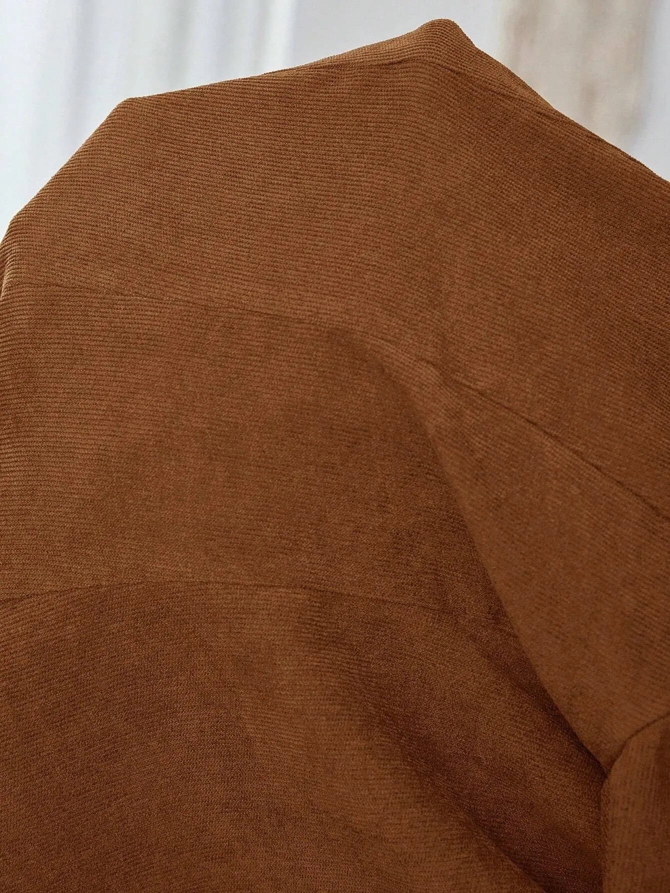 Brown men's single-breasted lapel coat with long sleeves on a hanger.