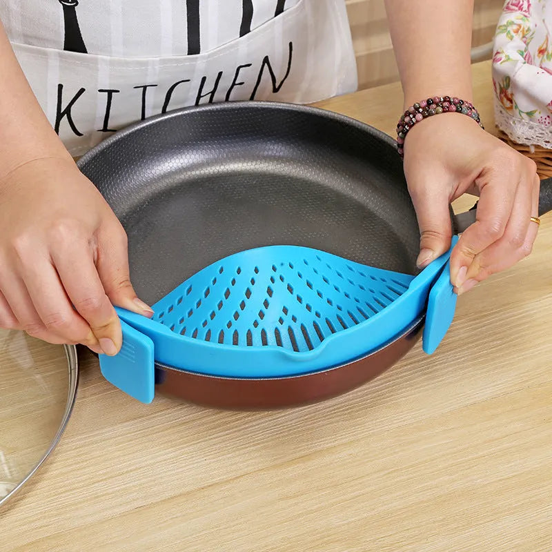 Silicone clip-on colander strainer in black with stainless steel clip attached to a pot rim for draining liquid