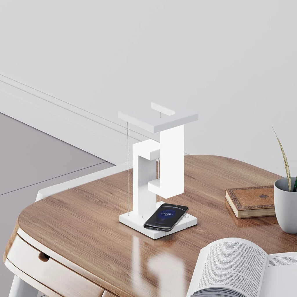 White magnetic suspension table lamp with wireless charging base, floating shade, and foldable bracket on a desk
