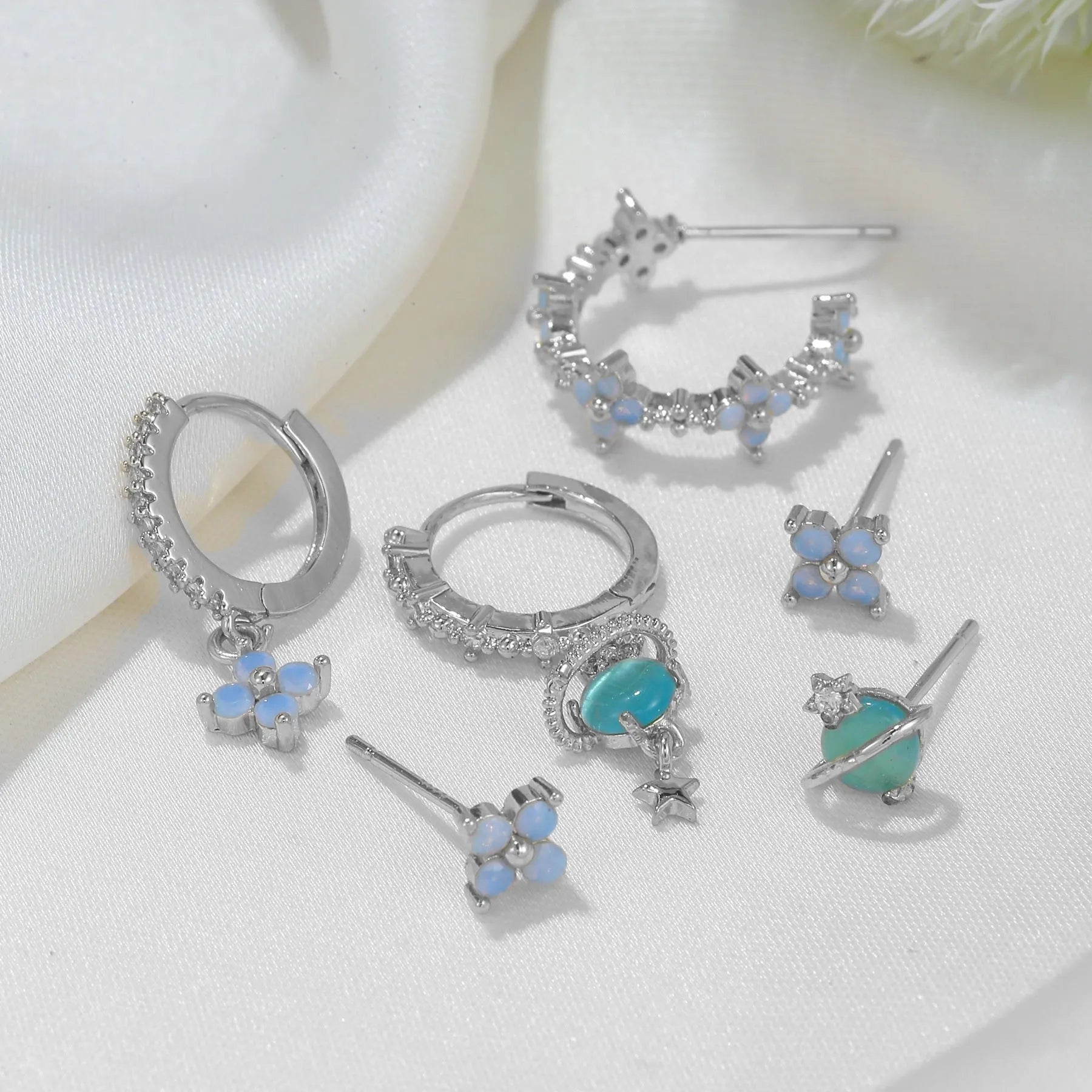 Gold and silver flower-shaped ear studs with zircon mosaic detail on a white background.