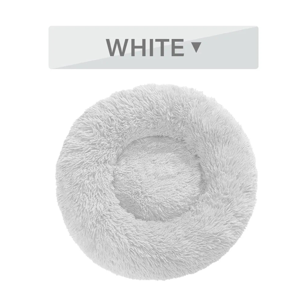 Fluffy donut-shaped pet bed in long plush fabric, shown in a light grey colour with a raised edge.