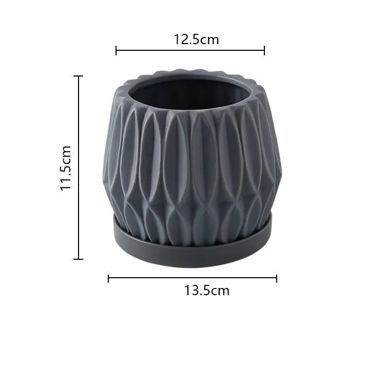 Grey small ceramic tabletop plant flowerpot on a desktop with a small green plant