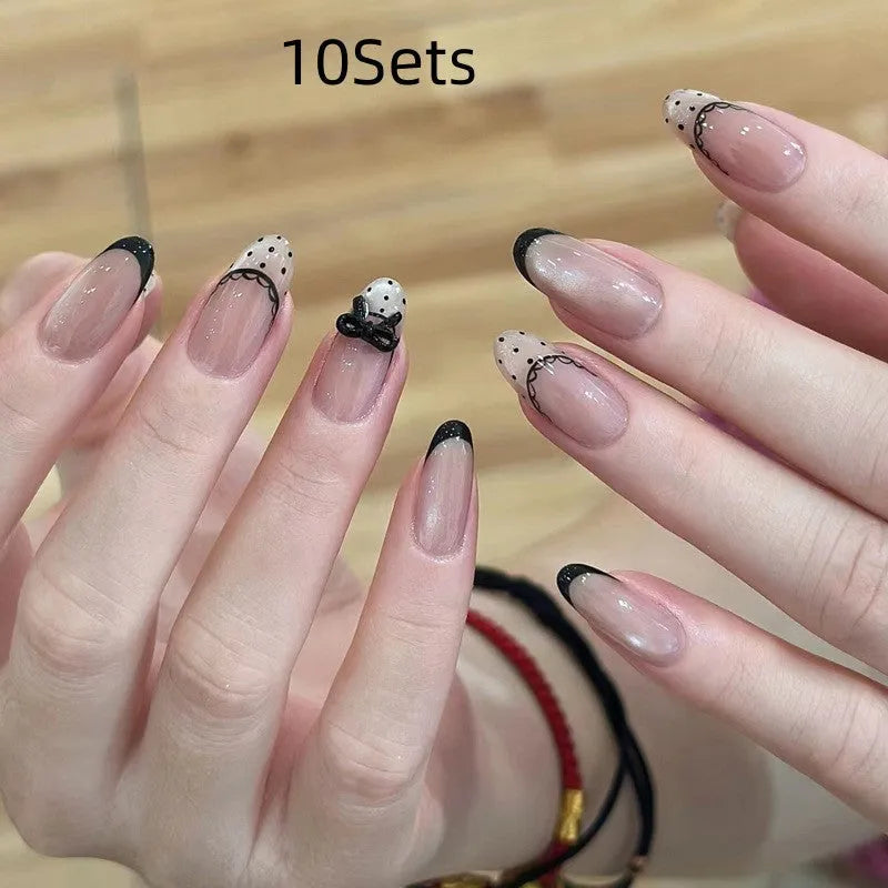 Assortment of sweet girl style false nails in various colours and designs, laid out on a table.