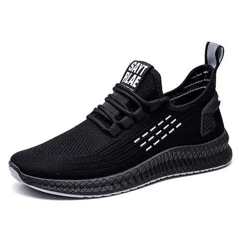 Men's low-top black casual trainers with cross-strap detail and flying weave upper, shown on a white background.