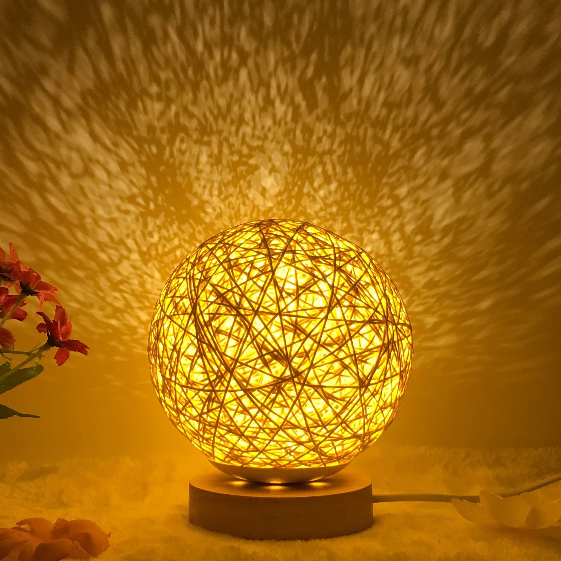 Rattan ball table lamp with woven shade and warm LED lighting on wooden surface