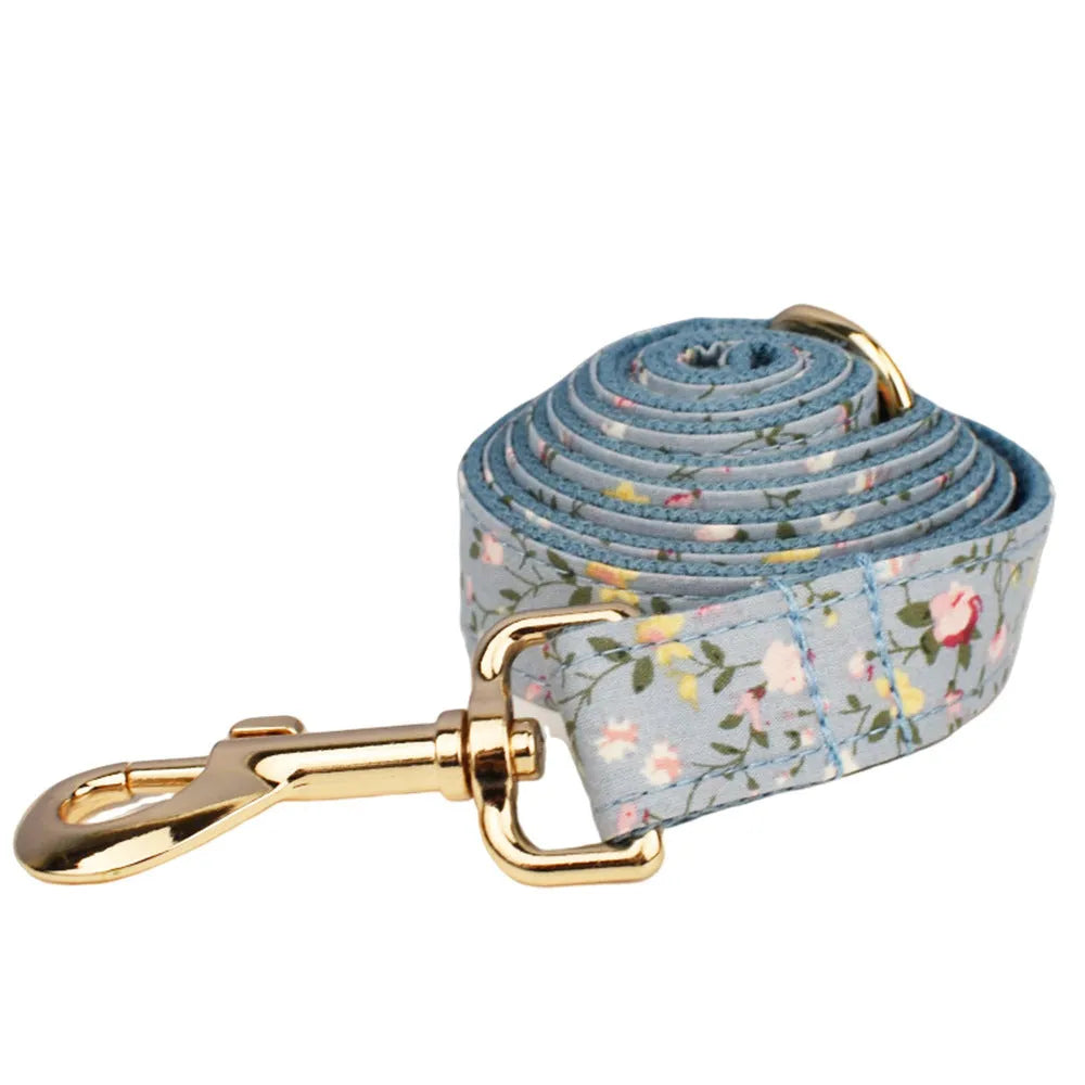 Blue floral patterned dog collar set with leash, bow tie, vest, and poop bag on a white background