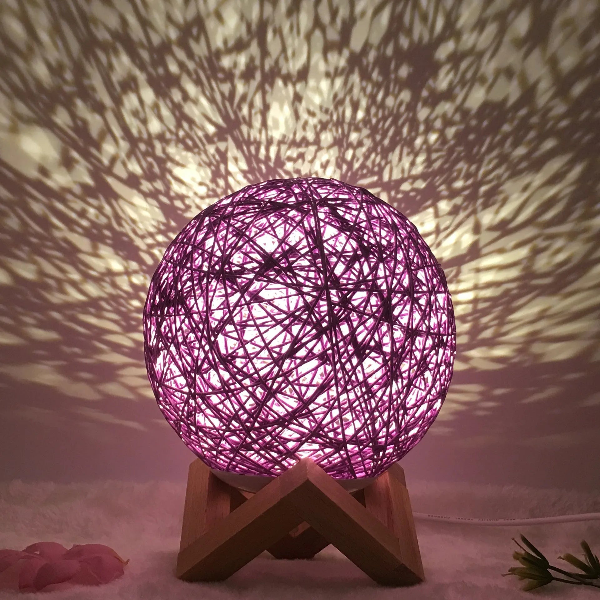 Rattan ball table lamp with woven shade and warm LED lighting on wooden surface