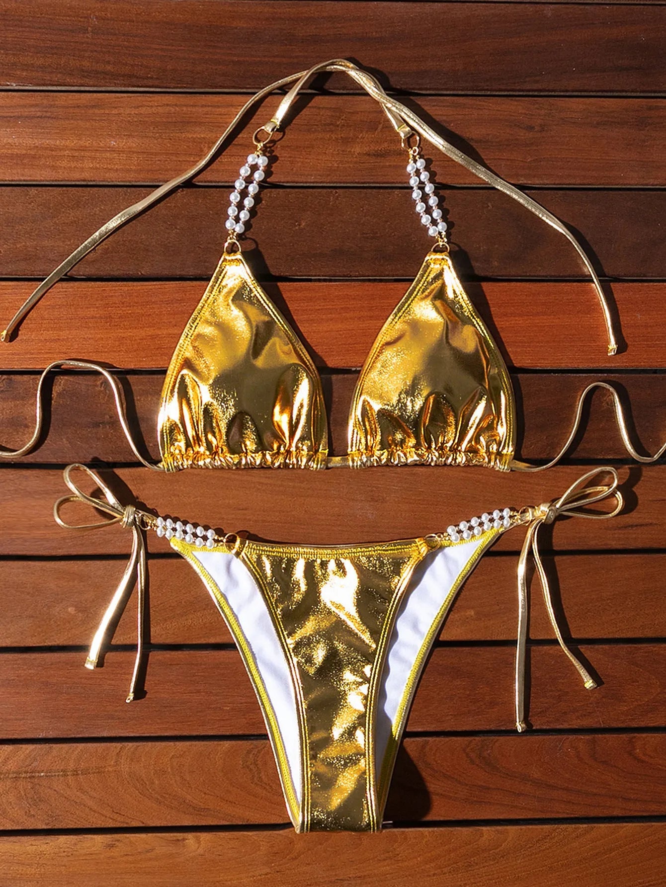 Gold women's halter bikini with front lace-up tie and decorative pearl chain detail.
