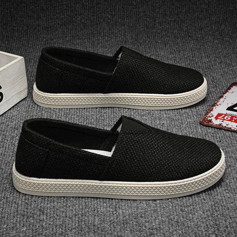 Men's beige linen canvas slip-on shoes with round toe and shallow cut design on a grey background.