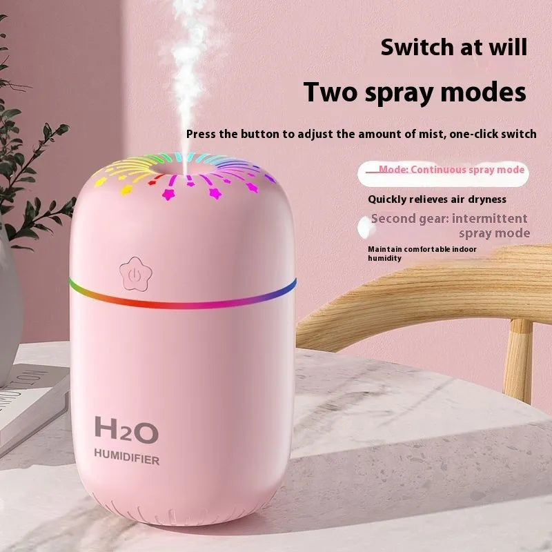 Small white USB desktop humidifier with water tank on a wooden desk.