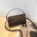 Cylindrical crossbody phone bag in soft genuine leather, shown in one of six colours including black or brown.