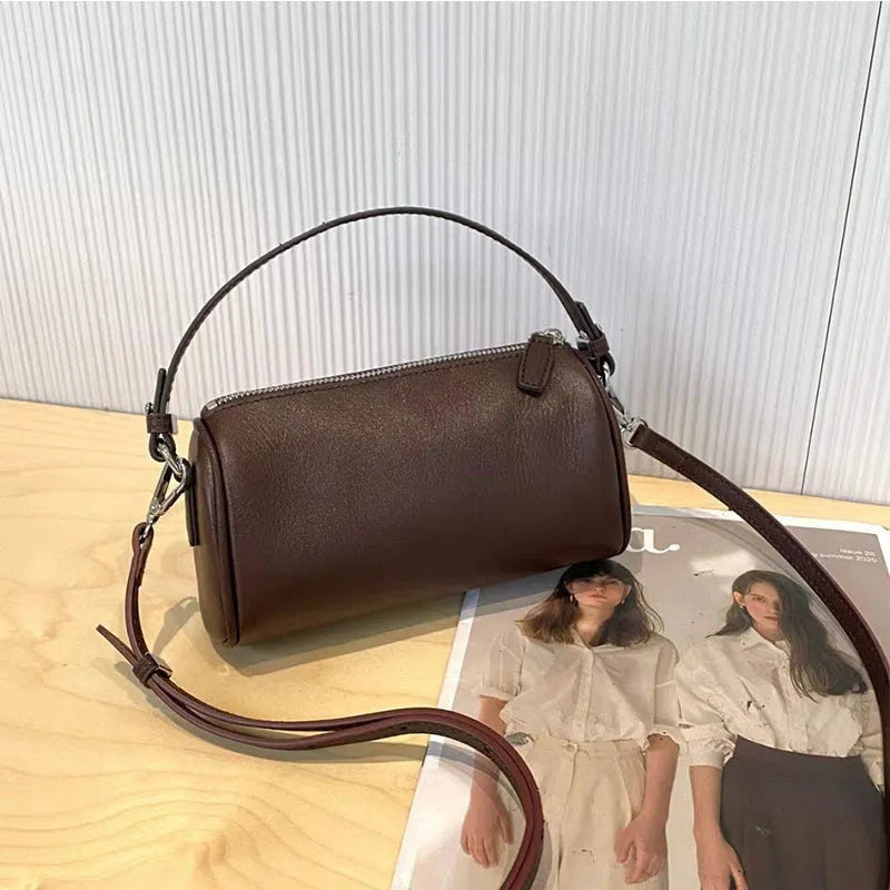 Cylindrical crossbody phone bag in soft genuine leather, shown in one of six colours including black or brown.