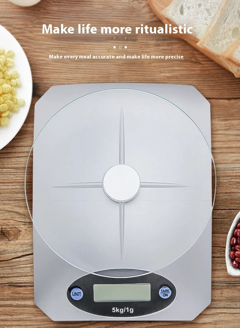 Simple mini kitchen electronic scale in silver white colour on a flat surface, showing weighing display.