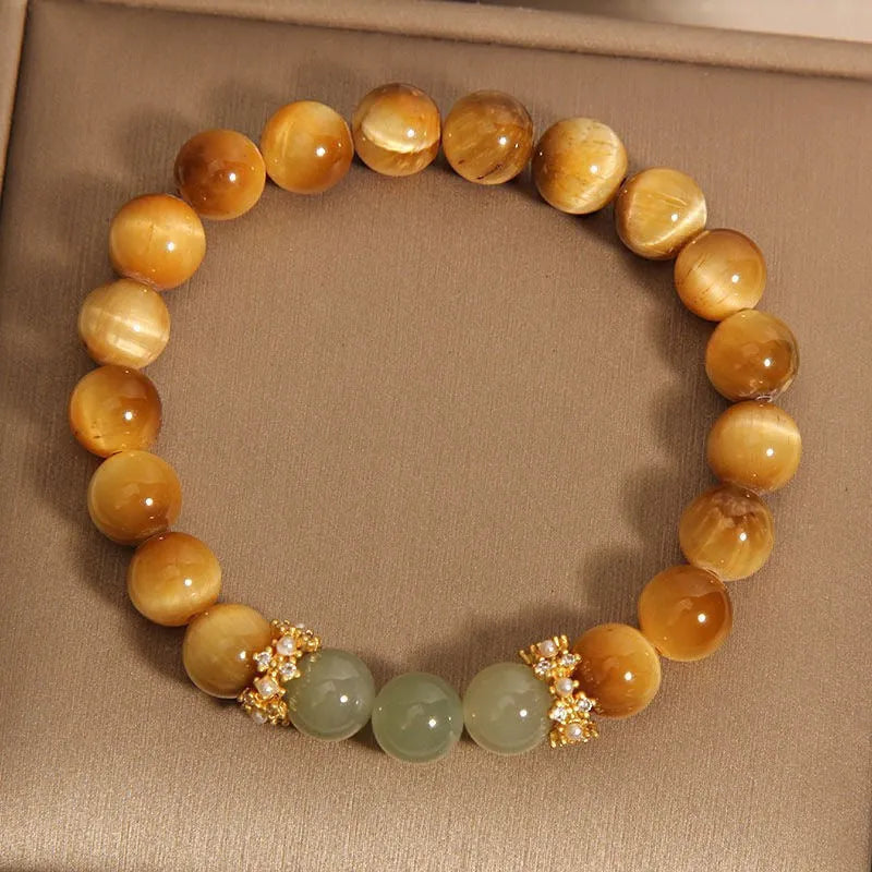 Natural yellow tiger's eye stone bracelet with gold gourd pattern on a white background.