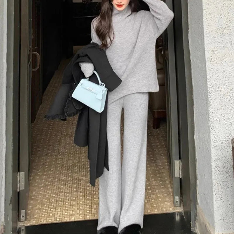 Women's beige acrylic knit long-sleeve sweater and matching wide-leg trousers set on a hanger.