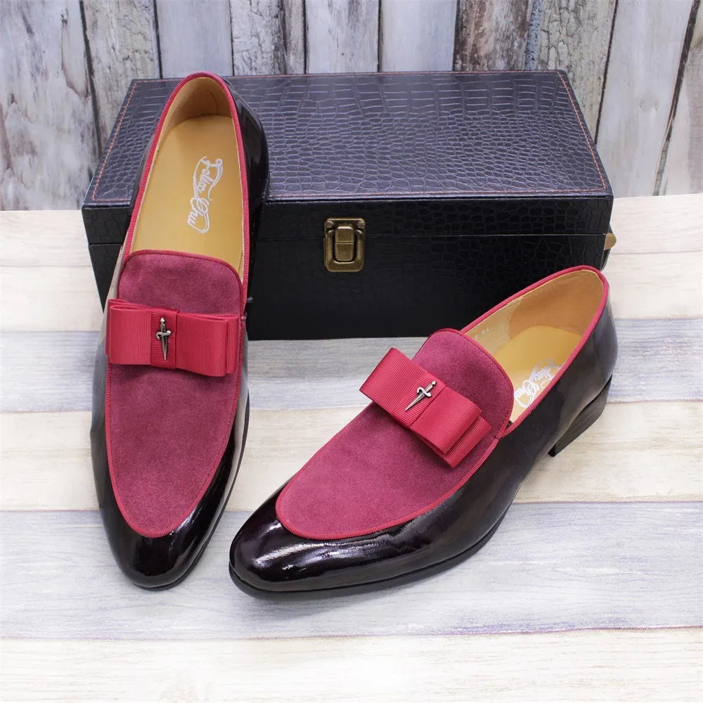 Men's glossy black patent leather tassel loafers with a low-top design and rubber sole on a wooden floor.
