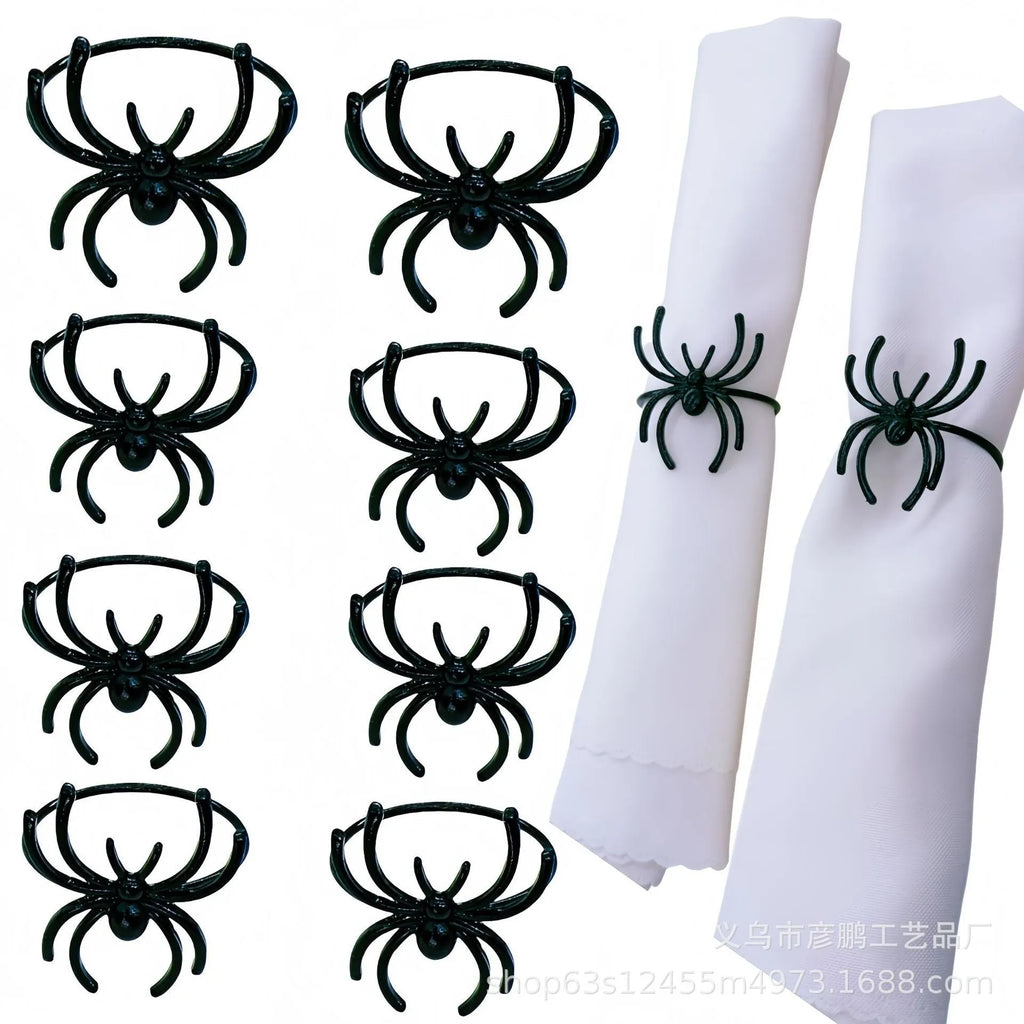 Set of six black alloy spider-shaped napkin rings on a dark tablecloth.