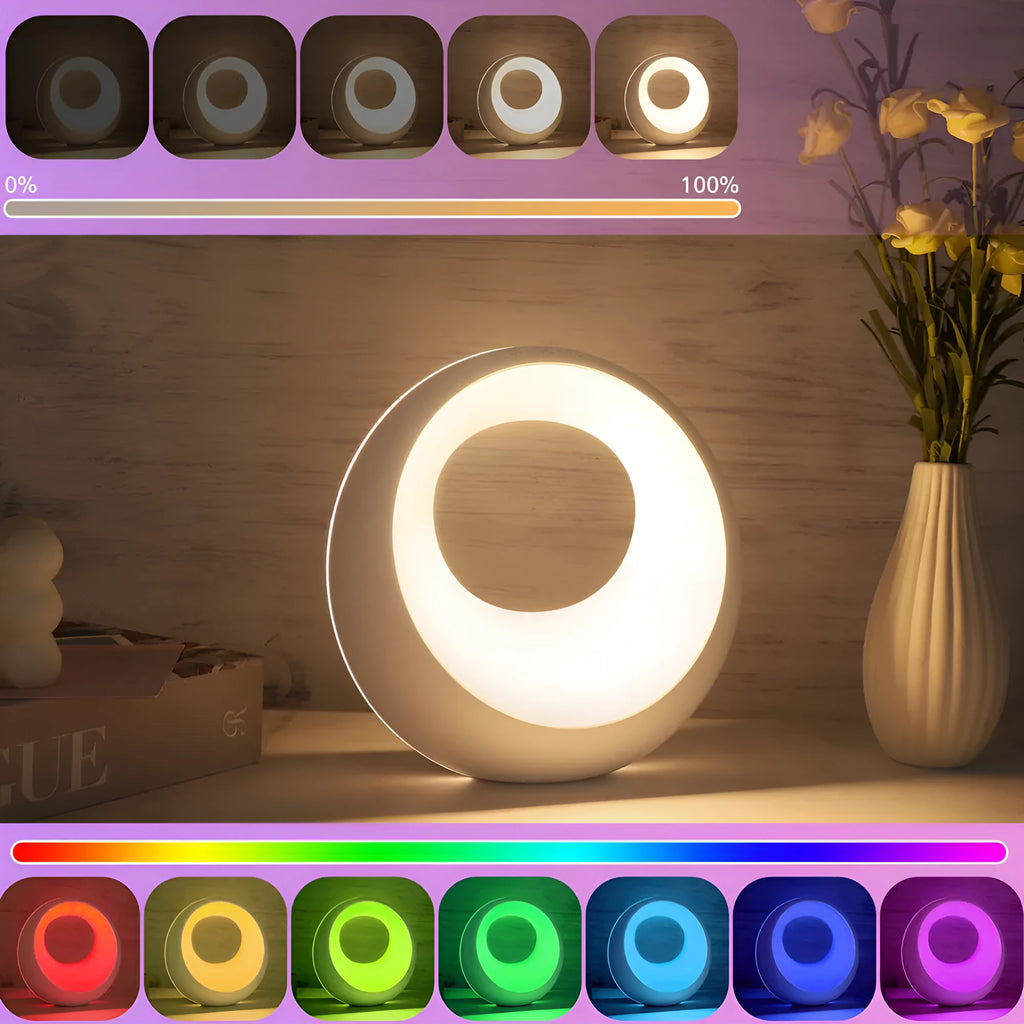 Small white desk lamp with remote control showing RGB colour-changing illumination on dark surface