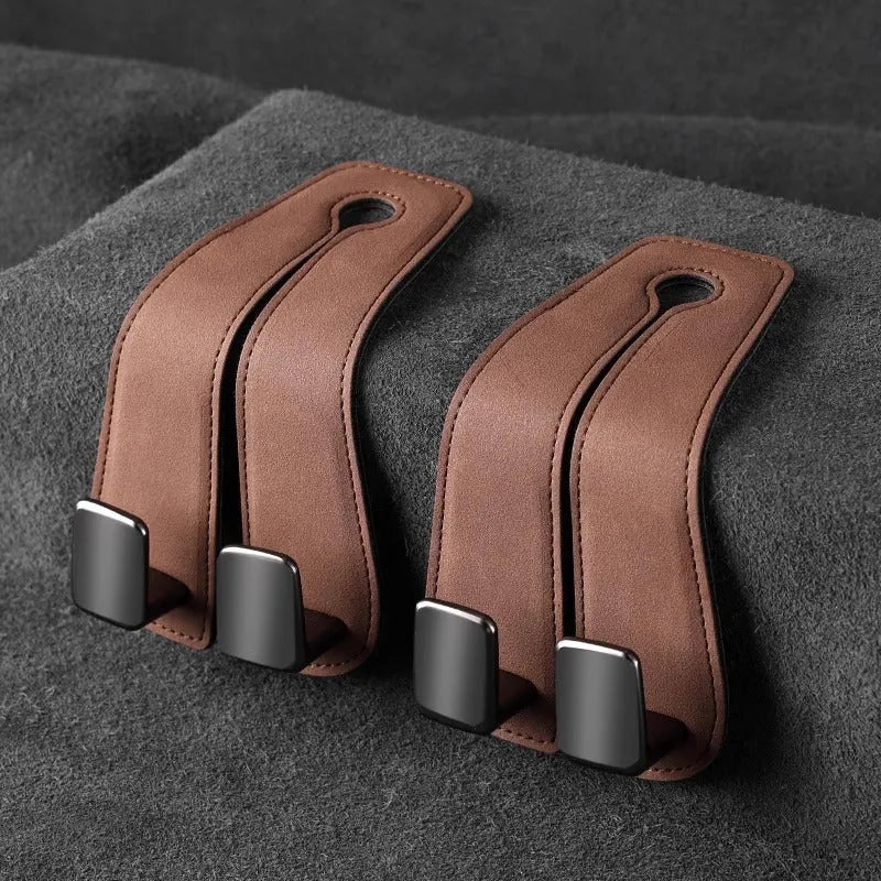 Black car seat hook with suede padding and flip-back design mounted on a grey car seat