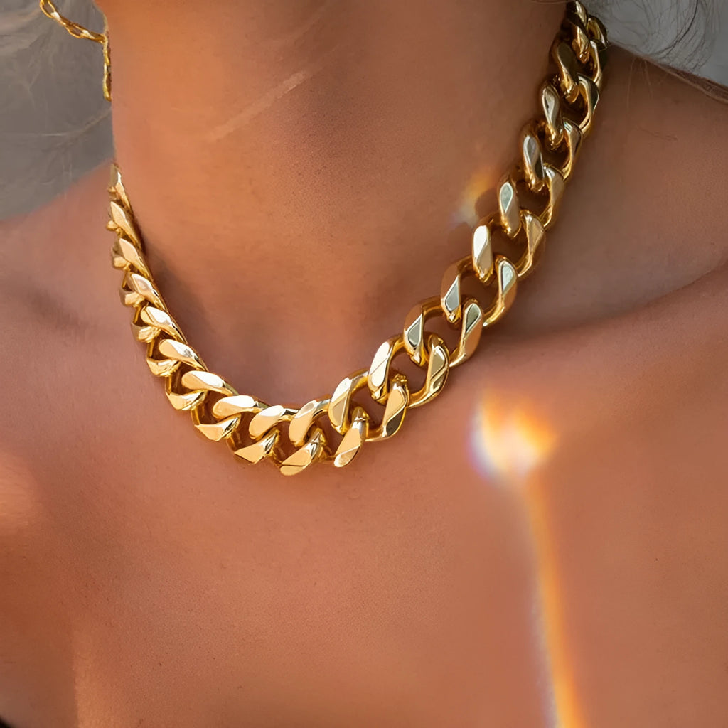 Gold electroplated women's necklace with thick chain and teardrop pendant on a grey background.