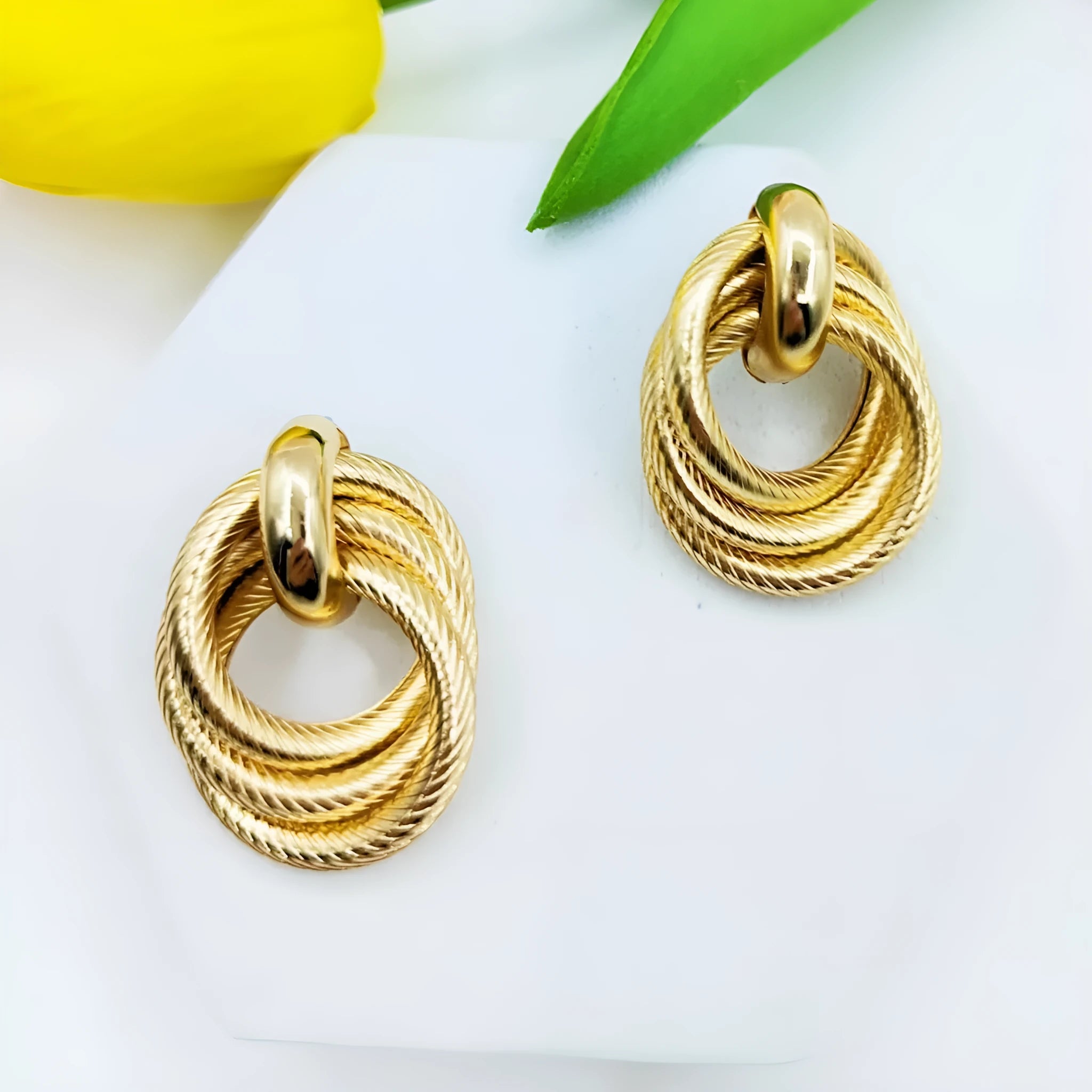 Gold geometric ring embossed twisted stud earrings on white background