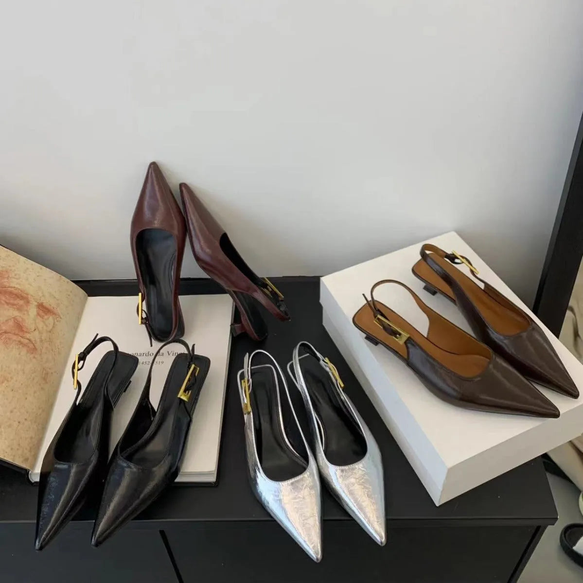 Women's black pointed toe low heel shoes with an ankle strap and rubber sole.