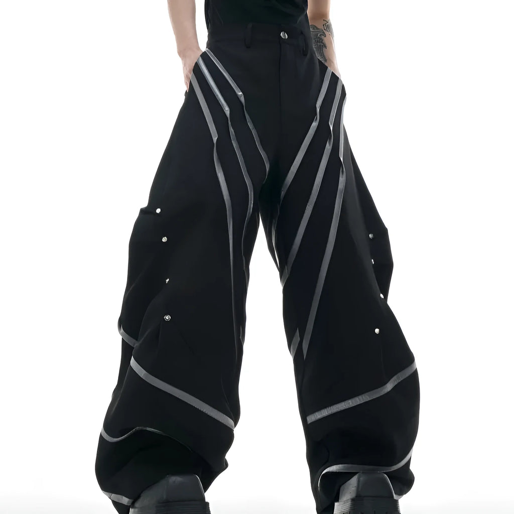 Men's black trousers with metal rivet pleats and a three-dimensional tailored cut.