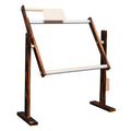 Vertical solid pine wood cross stitch embroidery frame with adjustable clamp on a desktop.