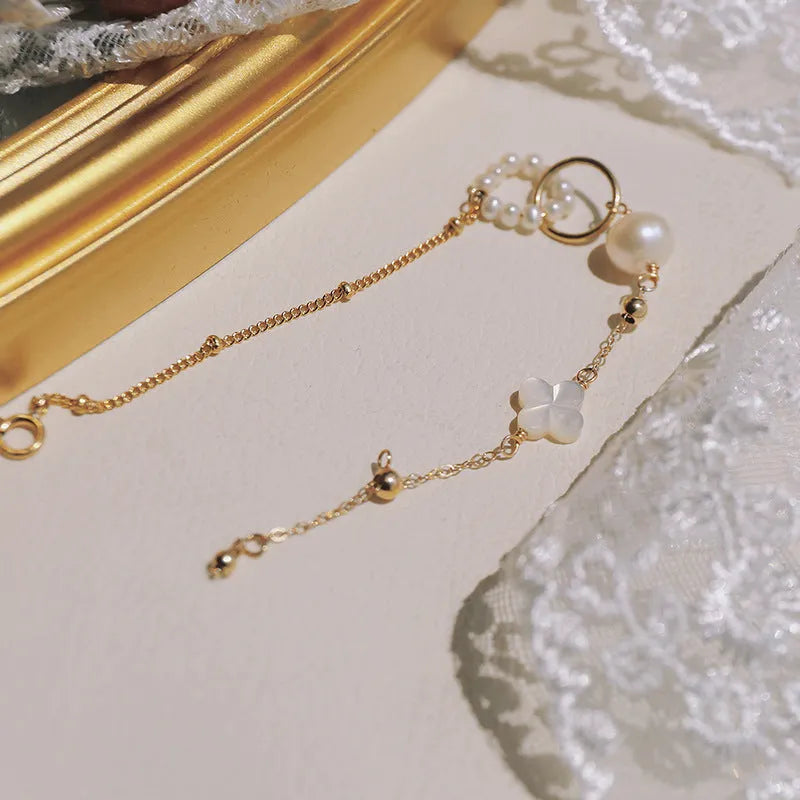 Women's natural freshwater pearl bracelet with gold-plated clasp and floral charm accents on a white background.
