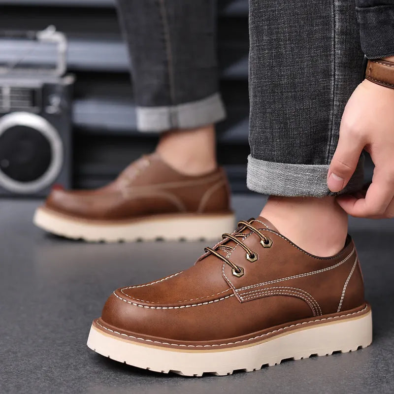 Men's black low-top Martin boots with a round toe and rubber sole on a plain background.