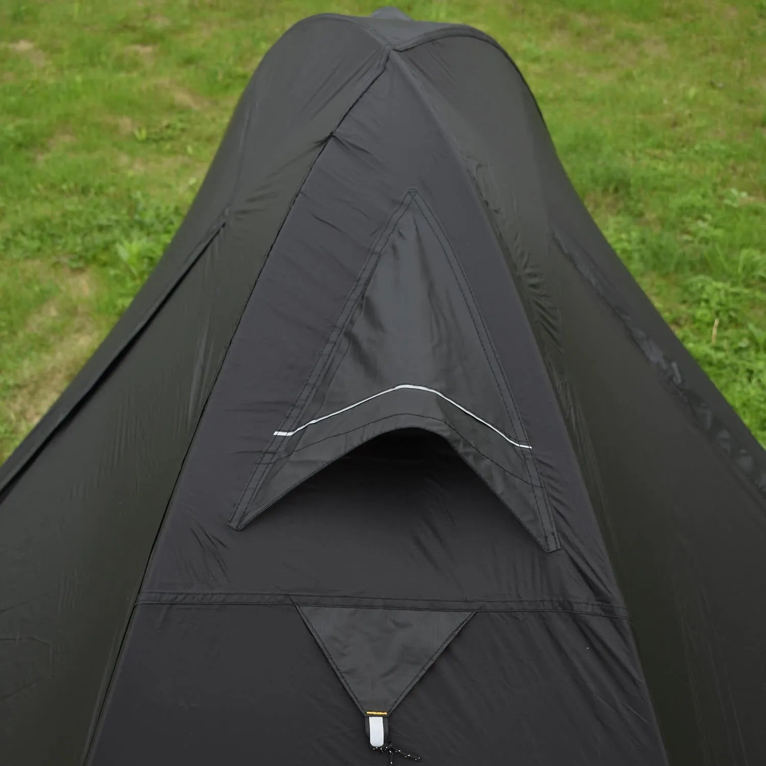 Single person hiking tent in orange pitched in a forest, showing aluminium poles and double-layer design with mesh panel.