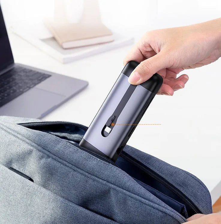 USB-C to multi-port docking station adapter with short cable shown next to a laptop, displaying HDMI, USB, and charging ports.