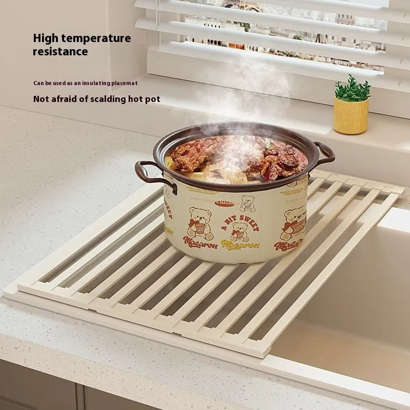 Milky White foldable stainless steel kitchen draining rack shown beside a sink, demonstrating its tri-fold mechanism.