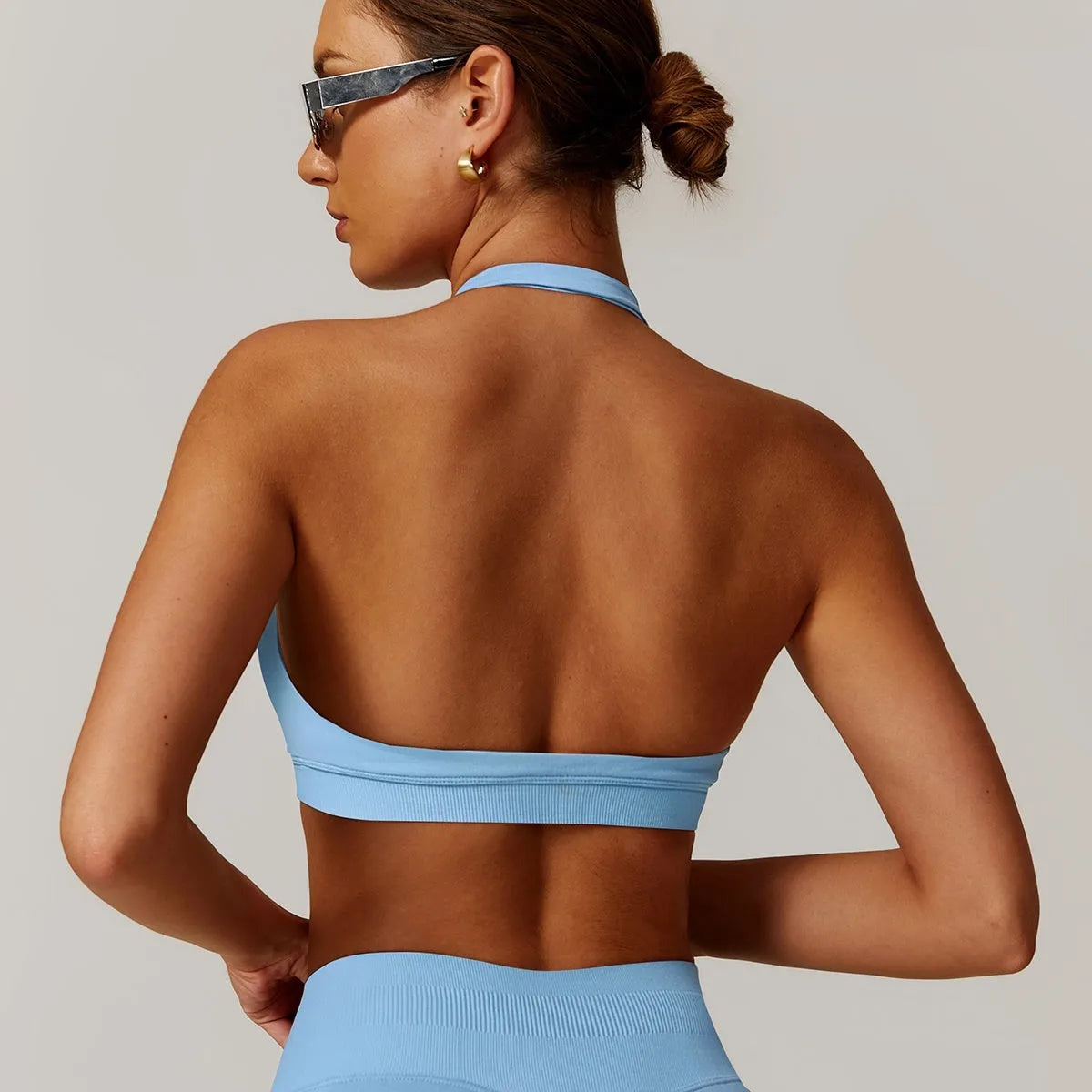 Women's black halter neck sports bra for yoga, shown from the front, with removable pads and a backless design.