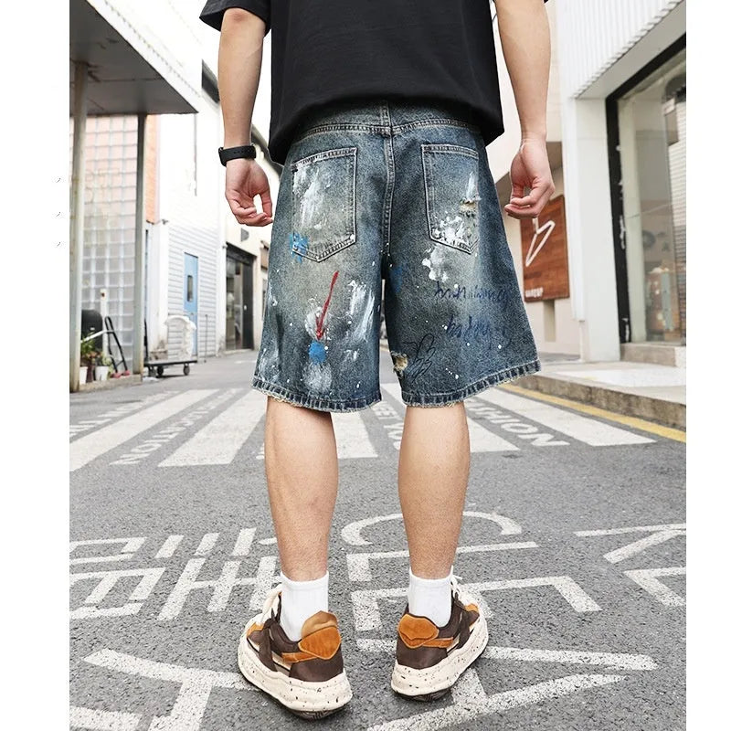 Blue men's ripped denim shorts with graffiti design and straight leg.