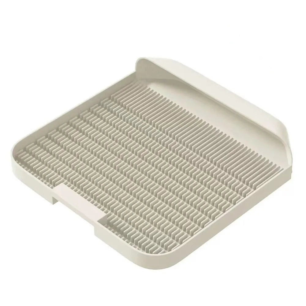 Large black cat litter pedal mat with slanted design next to a litter box.