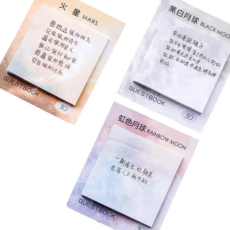 Square sticky notes notepad open to show planet oil painting designs including Earth and Rainbow Moon.