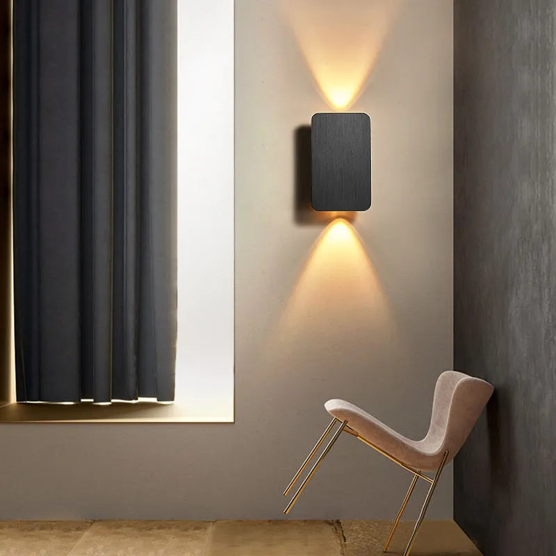 Minimalist black nordic wall lamp mounted beside a bed, emitting warm white light.
