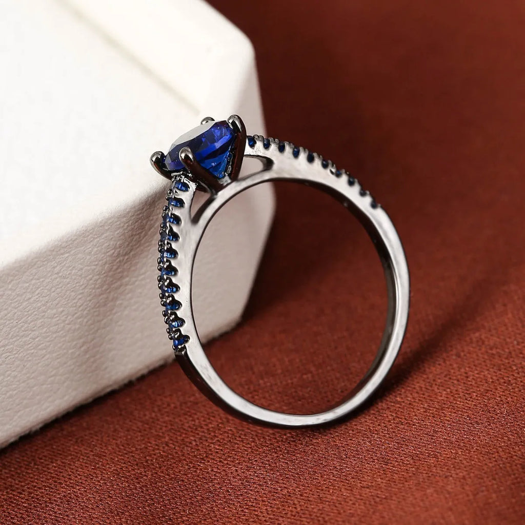 Hexagonal geometric zircon ring in copper with an electroplated gun black purple finish on a finger.