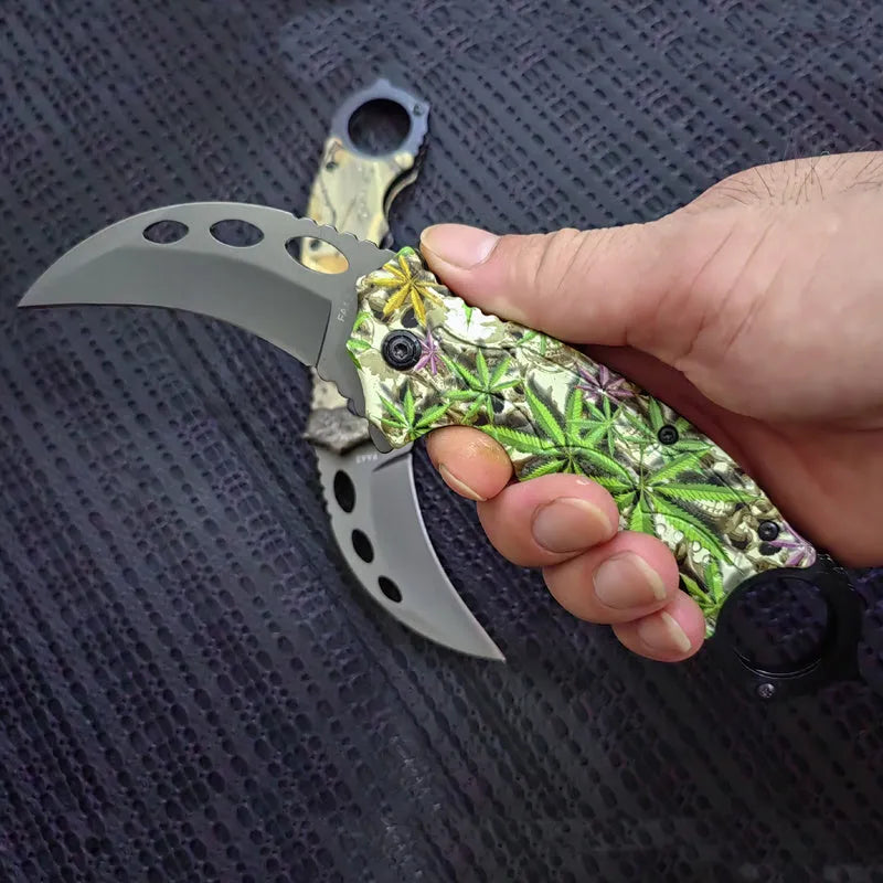 Folding claw knife with grey titanium blade and sour branch wood handle on a surface