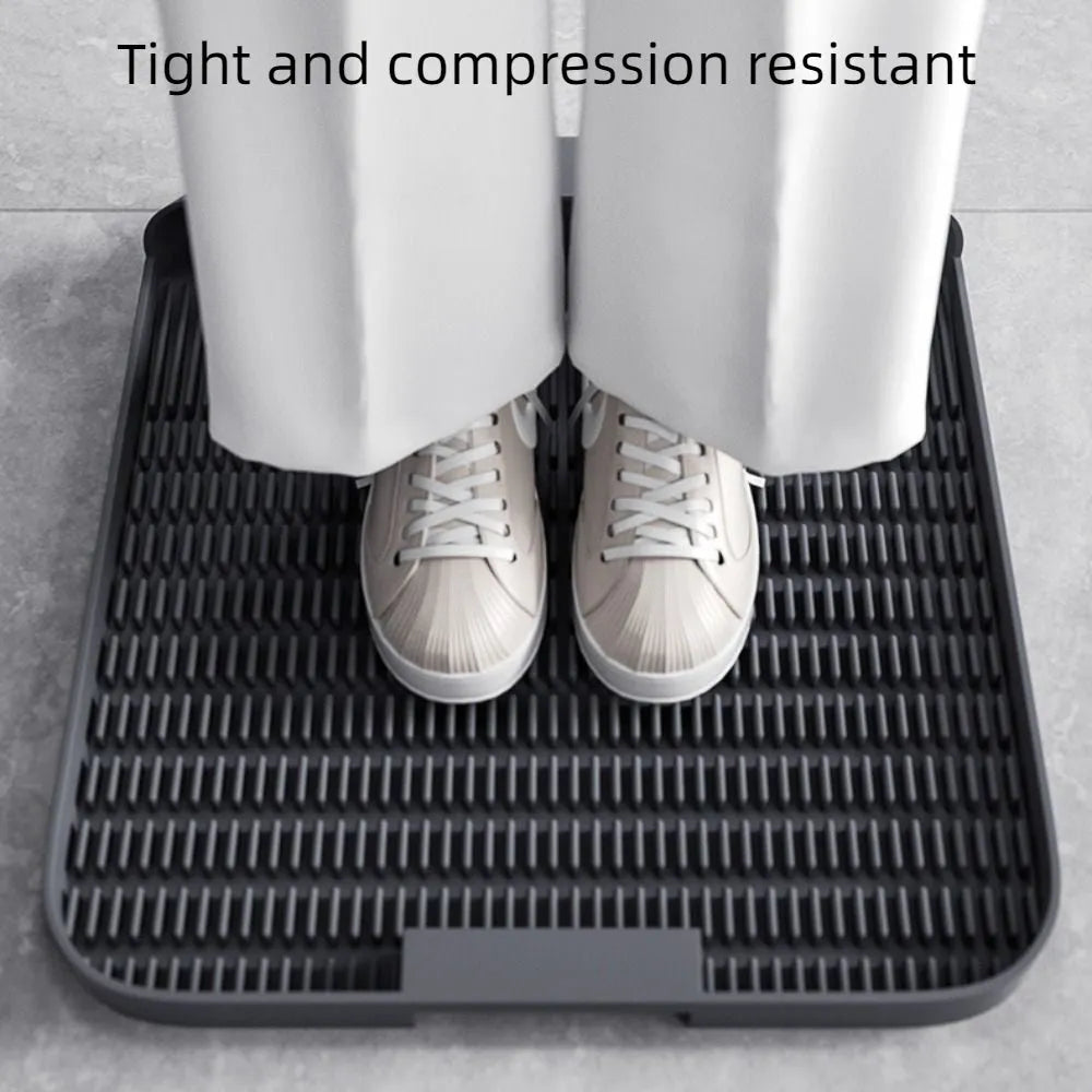 Large black cat litter pedal mat with slanted design next to a litter box.