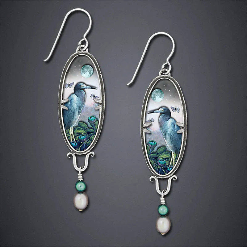 Silver drop earrings with a detailed bird and flower motif on a retro design.