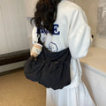 Soft foldable polyester crossbody bag in beige colour showing split pocket and crossbody strap.