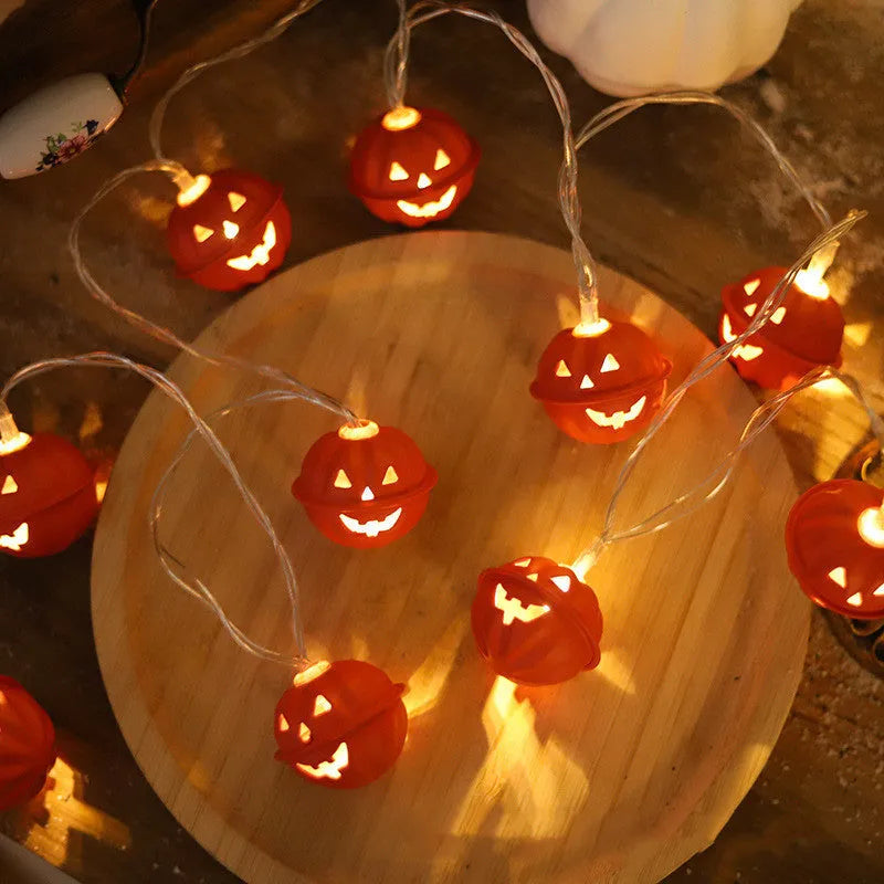LED Halloween string lights with warm white glow and iron pumpkin pendants on a dark background