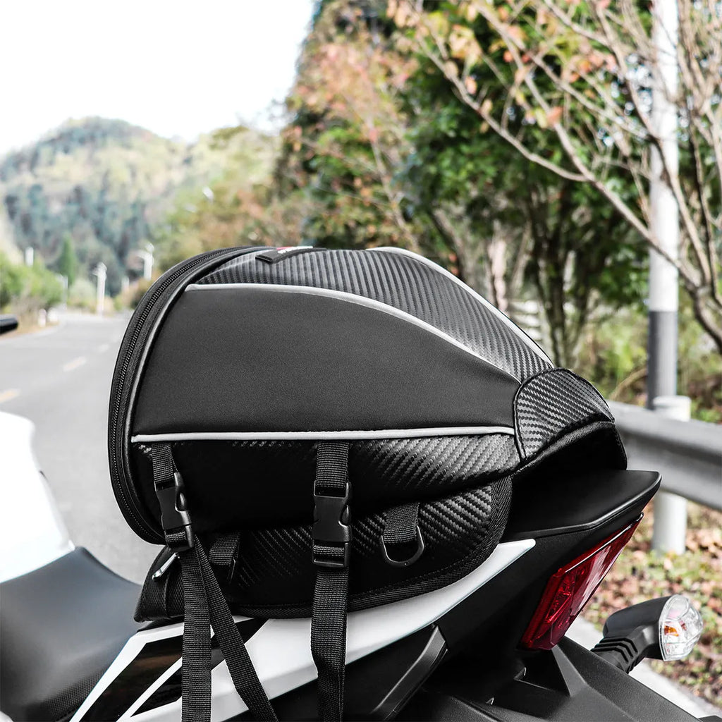 Black motorcycle seat bag with reflective strips, shown with carrying strap.