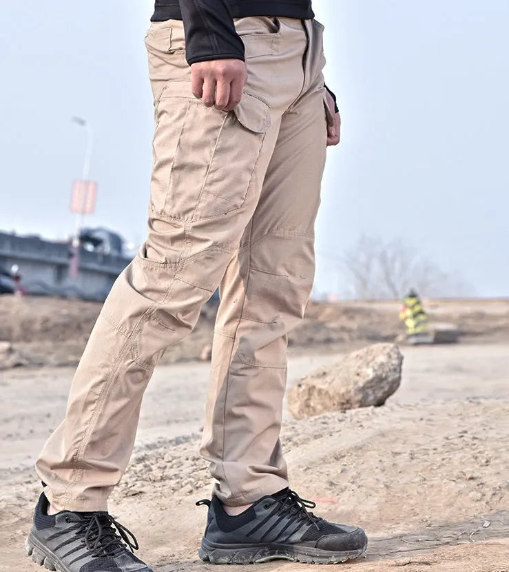 Outdoor multi-legged tactical pants in khaki cotton blend with multiple pockets on legs, shown against natural background
